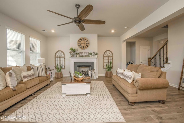 living area with recessed lighting, a fireplace, a ceiling fan, baseboards, and light wood-style floors