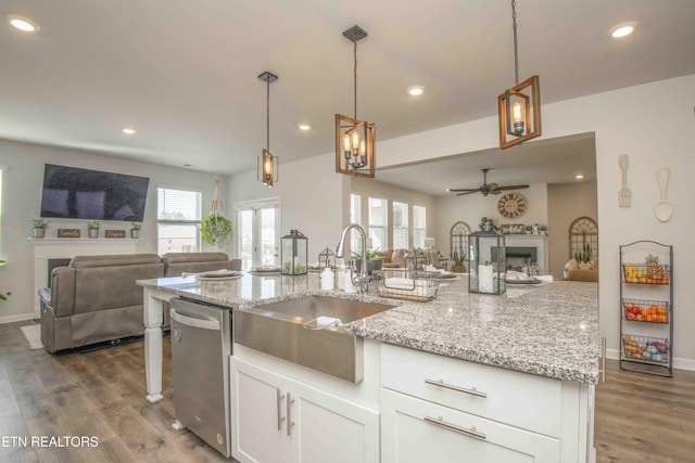 kitchen featuring pendant lighting, a fireplace, open floor plan, white cabinets, and a sink