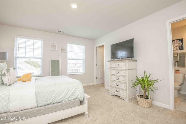 bedroom featuring light carpet, ensuite bath, visible vents, and baseboards