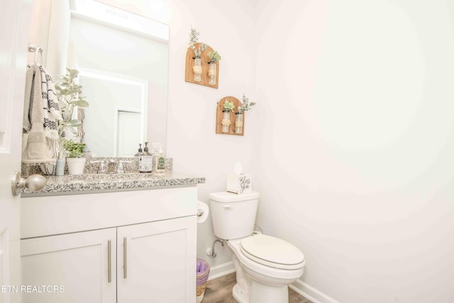 bathroom with toilet, baseboards, and vanity