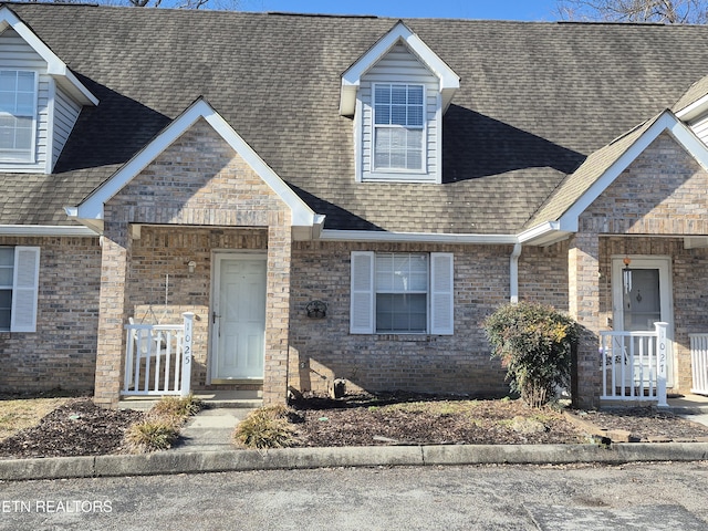 view of front of house featuring a shingled roof and brick siding