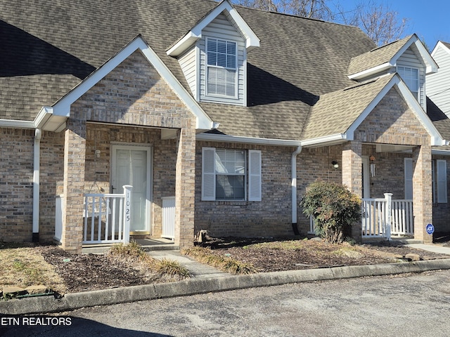 view of front facade with brick siding and roof with shingles