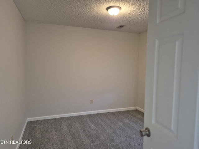 spare room with a textured ceiling, carpet flooring, and baseboards