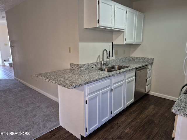 kitchen featuring dishwasher, a sink, white cabinetry, and baseboards