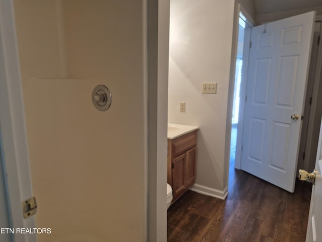 bathroom featuring toilet, vanity, baseboards, and wood finished floors