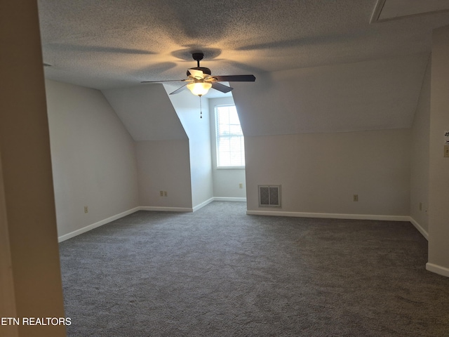 additional living space with ceiling fan, visible vents, dark colored carpet, and a textured ceiling