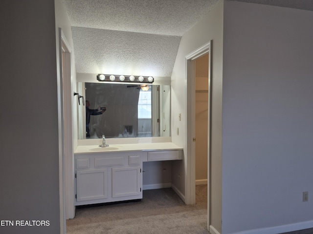 bathroom featuring baseboards, a textured ceiling, and vanity