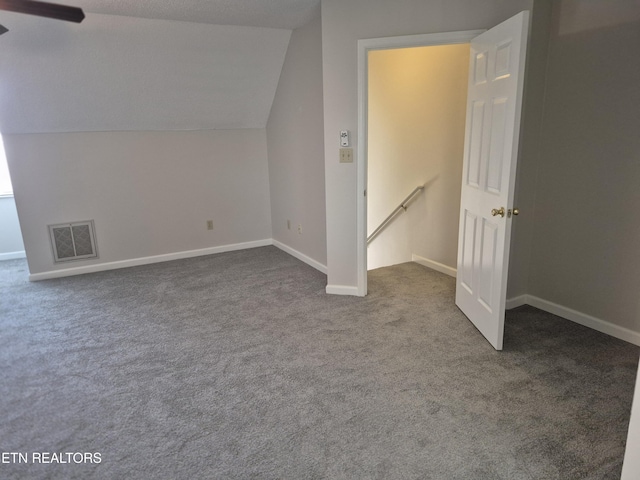 additional living space with carpet, visible vents, vaulted ceiling, and baseboards