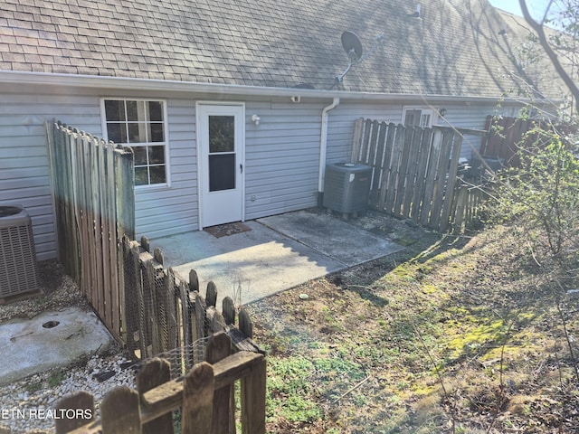 exterior space featuring a shingled roof, fence, central AC, and a patio