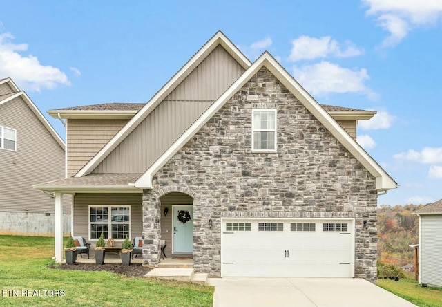 view of front of house featuring a garage, concrete driveway, stone siding, board and batten siding, and a front yard