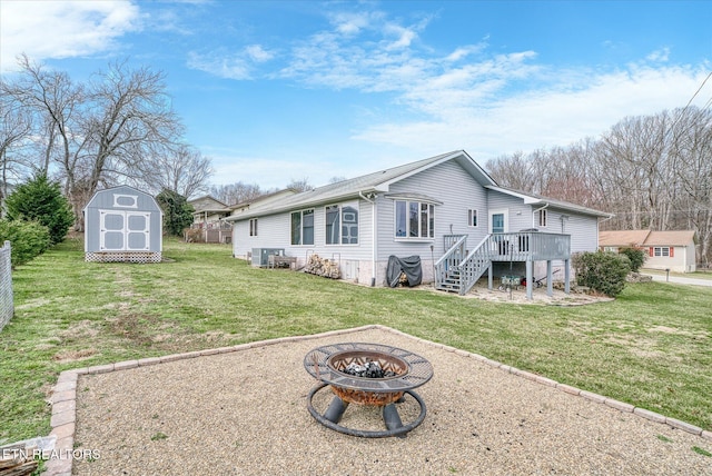 rear view of house featuring an outbuilding, a storage shed, an outdoor fire pit, a deck, and stairs