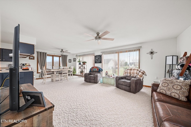 carpeted living area with ceiling fan, plenty of natural light, and baseboards