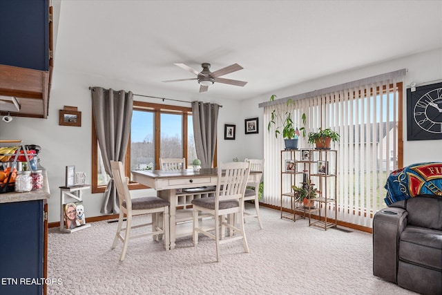 carpeted dining space featuring a ceiling fan and baseboards