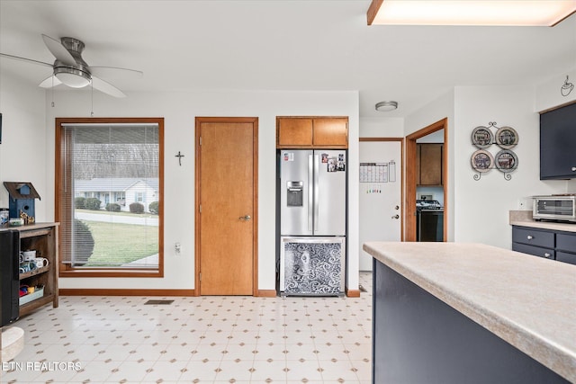 kitchen featuring a toaster, brown cabinets, light floors, light countertops, and stainless steel fridge with ice dispenser