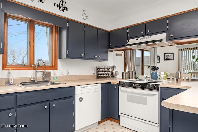 kitchen with white appliances, under cabinet range hood, light countertops, and a sink