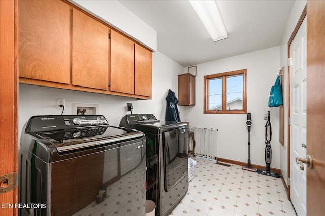 laundry area with cabinet space, baseboards, radiator, light floors, and separate washer and dryer