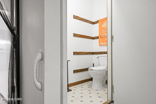 bathroom featuring toilet, baseboards, and tile patterned floors