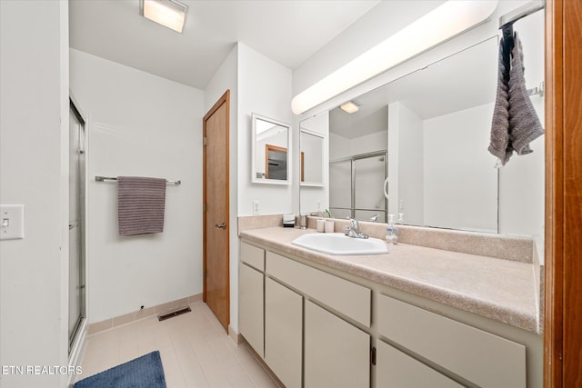 full bath featuring a stall shower, vanity, visible vents, and baseboards