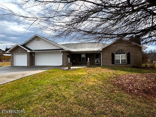 ranch-style home featuring a garage, concrete driveway, and a front yard