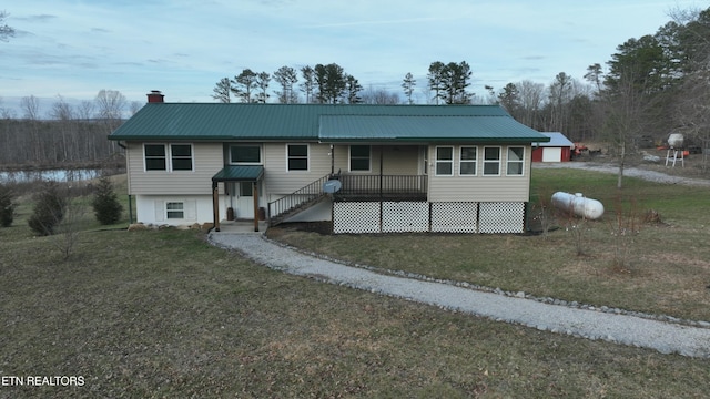 view of front of house featuring a chimney, metal roof, and a front yard