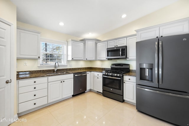 kitchen featuring light tile patterned flooring, recessed lighting, a sink, appliances with stainless steel finishes, and dark stone countertops