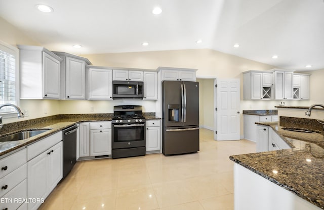 kitchen with dark stone countertops, stainless steel appliances, and a sink