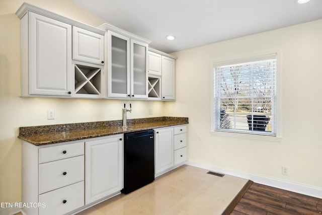 kitchen with visible vents, white cabinets, dark stone counters, baseboards, and fridge