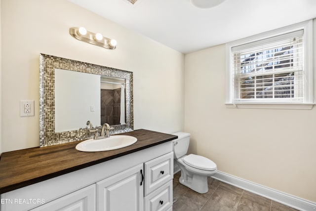 bathroom featuring toilet, baseboards, and vanity