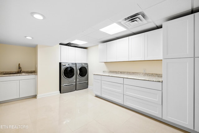 laundry room with cabinet space, visible vents, washing machine and dryer, a sink, and baseboards