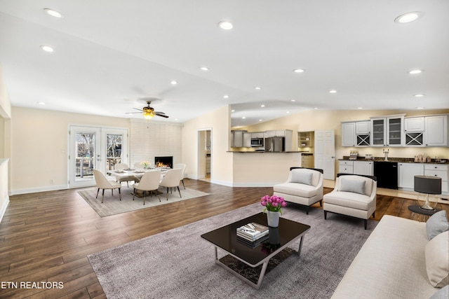 living area with a large fireplace, dark wood-style flooring, vaulted ceiling, and recessed lighting