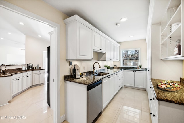 kitchen featuring dark stone counters, white cabinetry, a sink, and stainless steel dishwasher