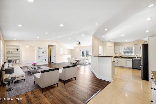 living room featuring lofted ceiling, light wood-type flooring, a wealth of natural light, and built in features