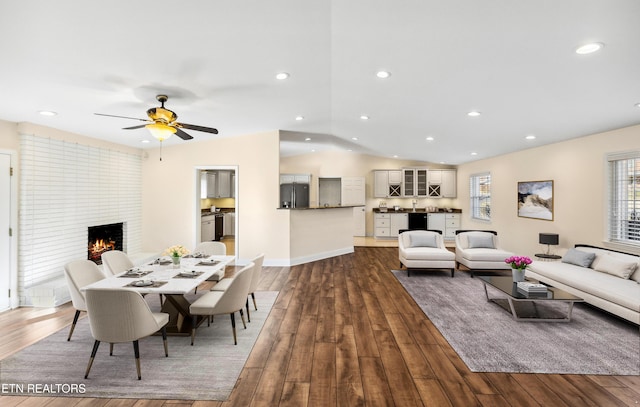 living room with a brick fireplace, vaulted ceiling, and dark wood finished floors