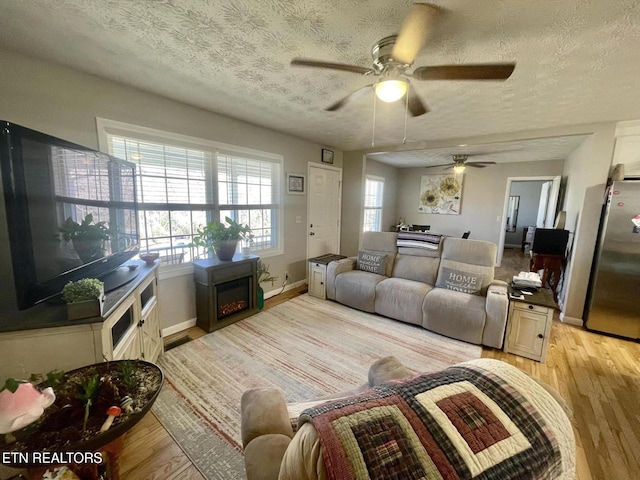 living area featuring light wood-style floors, baseboards, and a textured ceiling