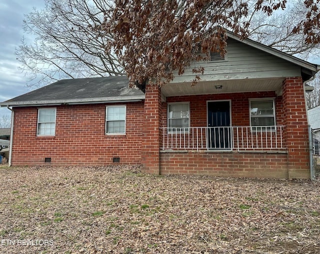 back of property with covered porch, brick siding, and crawl space