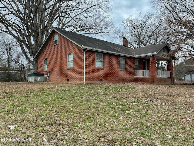 view of side of property with crawl space, brick siding, a lawn, and a chimney