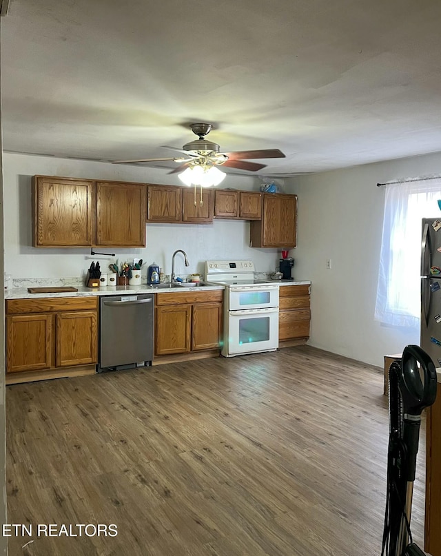 kitchen featuring range with two ovens, brown cabinets, a sink, and stainless steel dishwasher