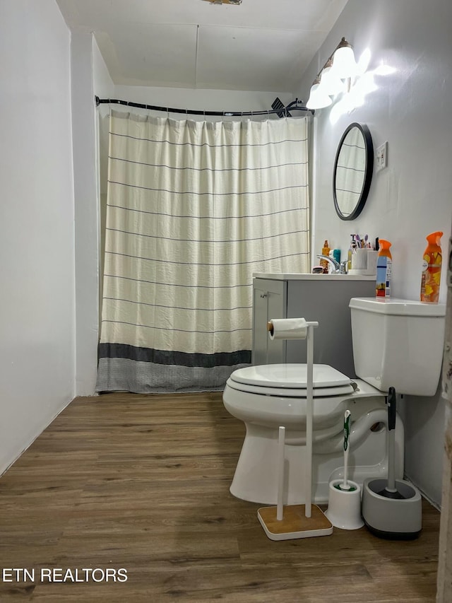 full bath featuring a shower with shower curtain, toilet, and wood finished floors