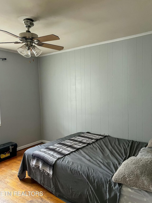 bedroom featuring ornamental molding, wood finished floors, and a ceiling fan