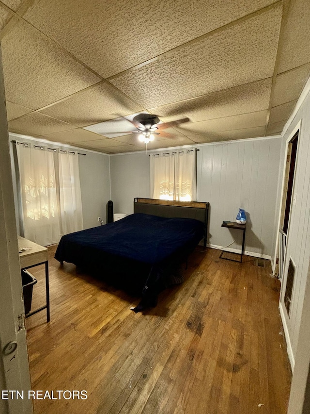 unfurnished bedroom with a ceiling fan, a paneled ceiling, visible vents, and wood finished floors