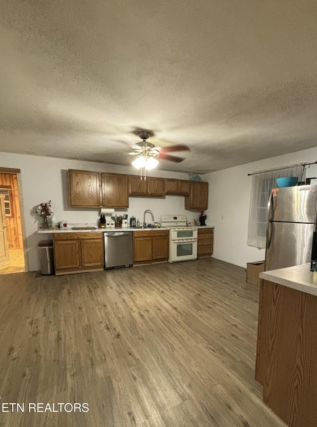 kitchen featuring stainless steel appliances, wood finished floors, a sink, and light countertops