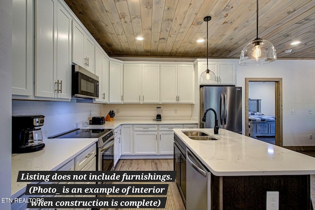 kitchen with a kitchen island with sink, a sink, white cabinetry, appliances with stainless steel finishes, and decorative light fixtures