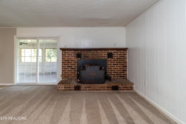 unfurnished living room with baseboards, ornamental molding, carpet flooring, a wood stove, and a textured ceiling