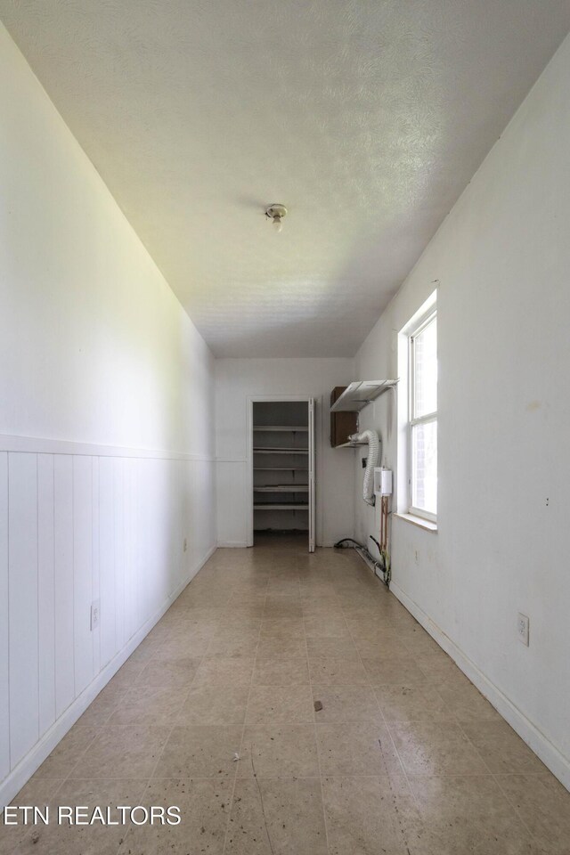 empty room with a textured ceiling and wainscoting