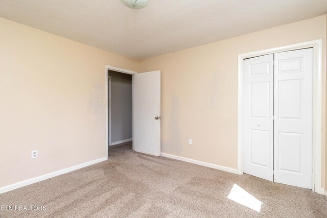 unfurnished bedroom with a closet, baseboards, and carpet
