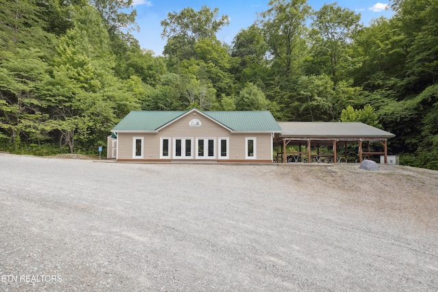 exterior space featuring driveway, a carport, and a view of trees