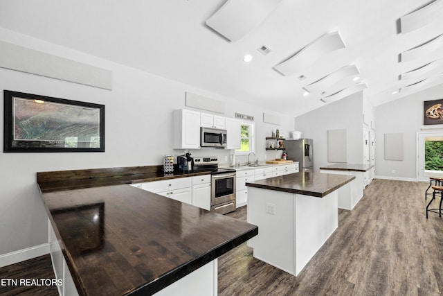 kitchen featuring a sink, visible vents, a peninsula, dark countertops, and appliances with stainless steel finishes