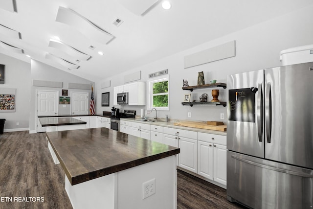 kitchen with dark wood-style flooring, white cabinetry, vaulted ceiling, a peninsula, and appliances with stainless steel finishes