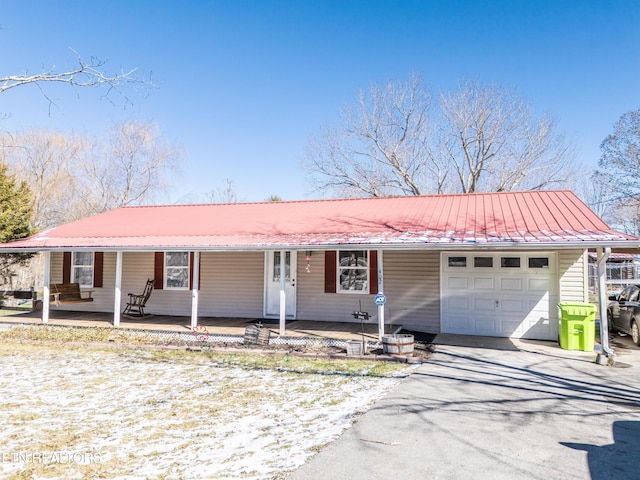 single story home with a garage, covered porch, aphalt driveway, and metal roof