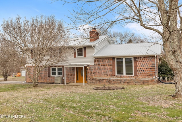 view of front of house featuring brick siding, a chimney, and a front lawn